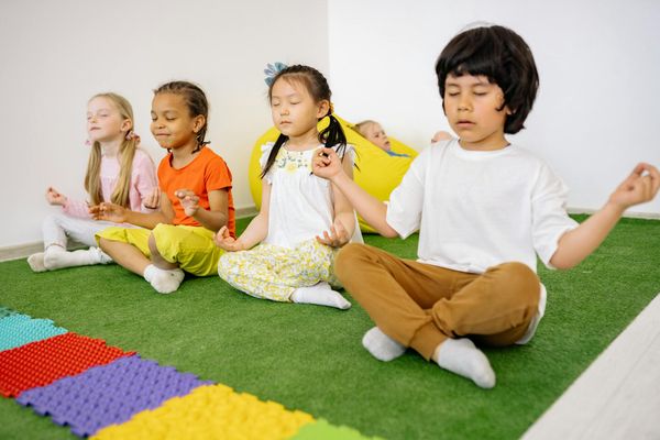 Group of children practicing gentle yoga stretches on colorful mats.